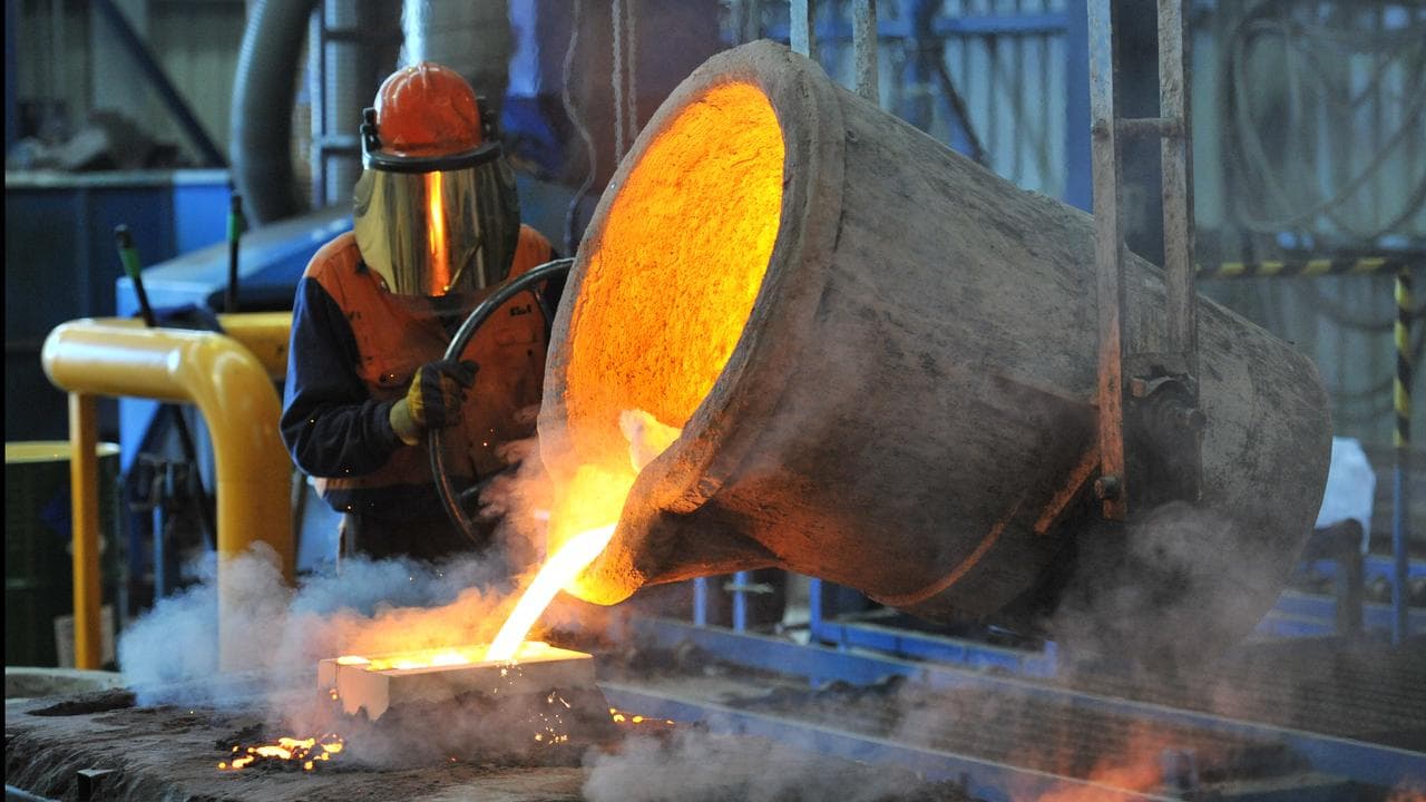 Factory worker pours molten iron