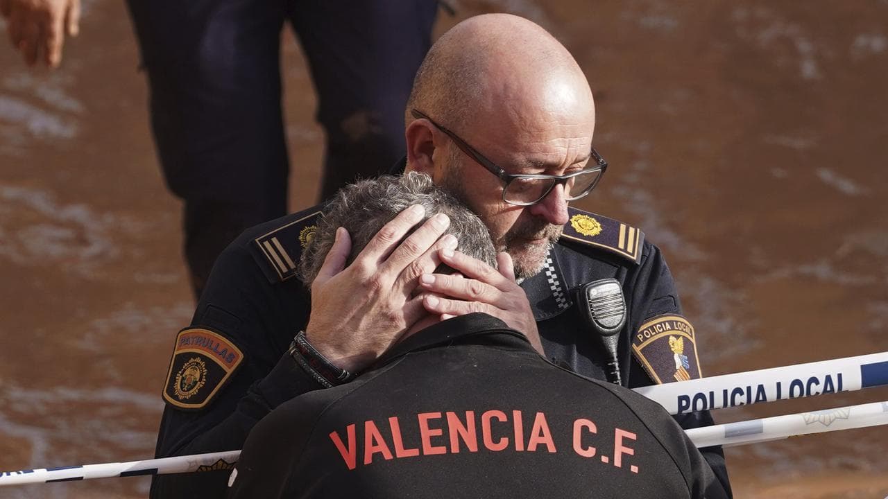 Police react to the news of a colleague dying in the floods in Spain