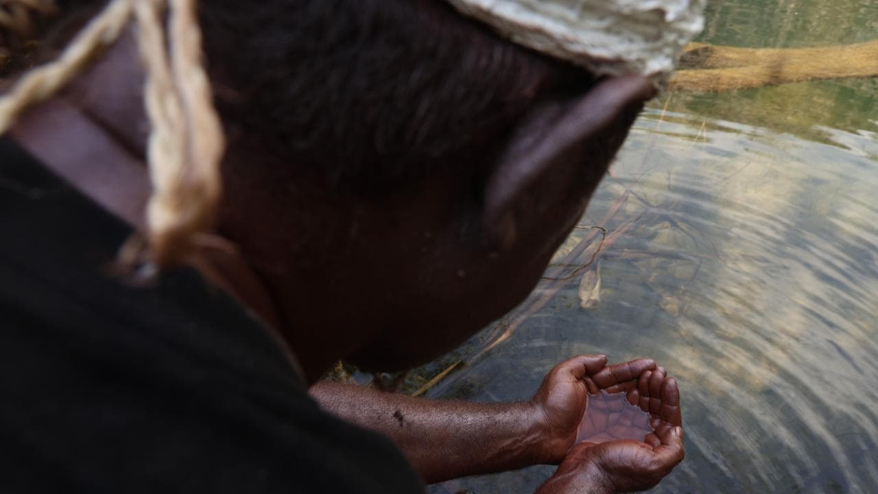 Man washes his hand in waterhole