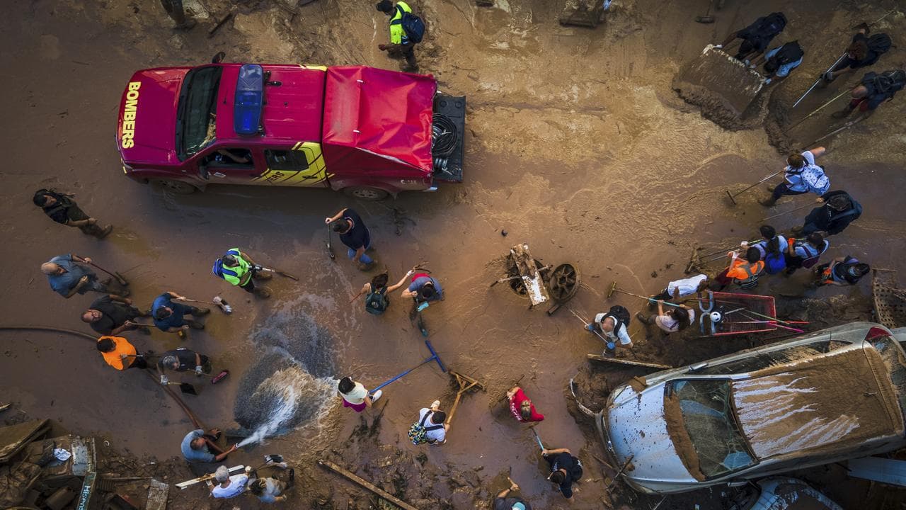Volunteers and residents clean the mud four days after flash floods