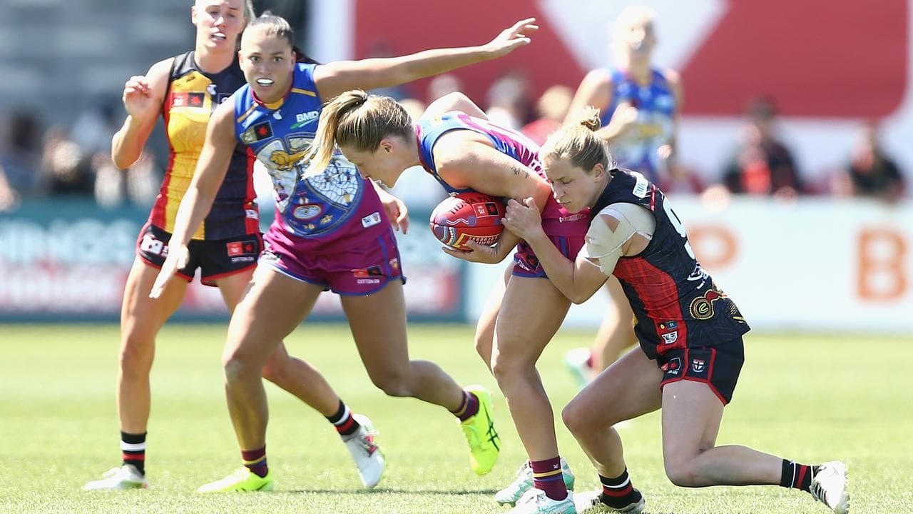 Lion Isabel Dawes looks to get a handball away in a tackle.