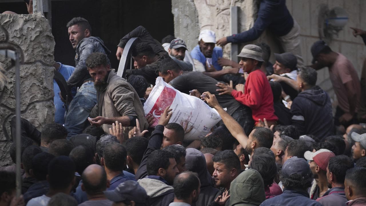 Palestinians receive bags of flour distributed by UNRWA in Gaza