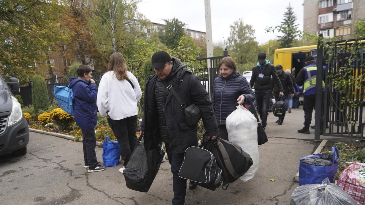 People carry their possessions after fleeing Kupiansk