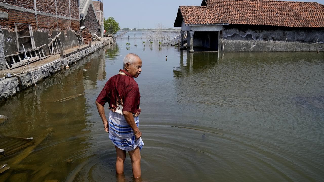 A man walks on a flooded pathway in Central Java.
