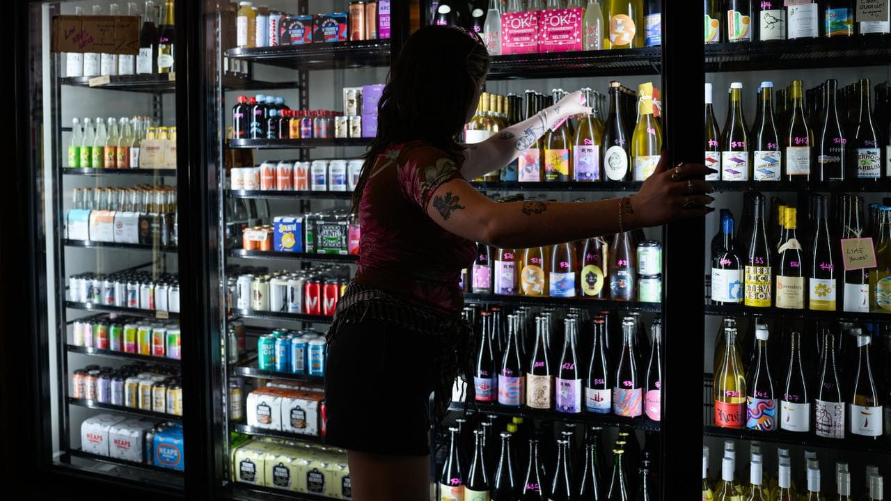 A worker stocks fridges at a Paddington wine store