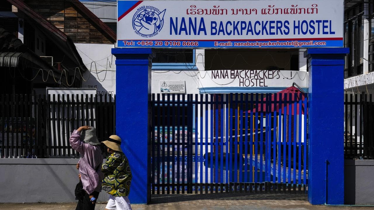 Foreign tourists walk past the closed Nana Backpackers hostel
