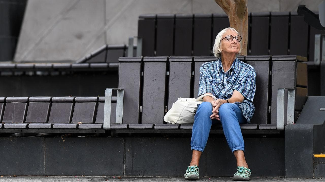 An elderly woman sits on a bench