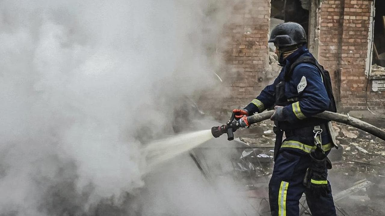 Rescue worker puts out a fire of a burned car in Kharkiv
