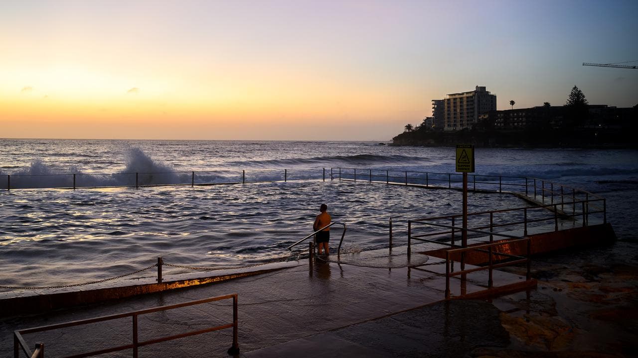 Swimmers are seen during first light at Cronulla Beach in Sydney