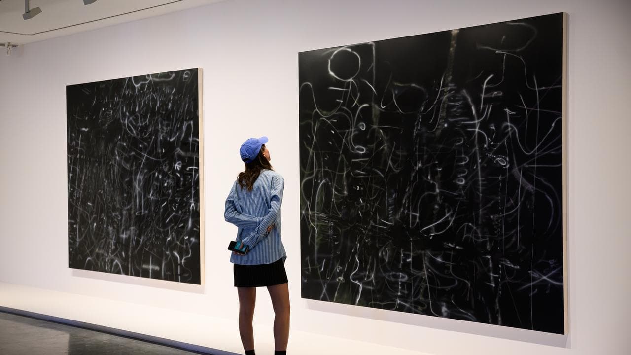 A person views some of Julie Mehretu's work