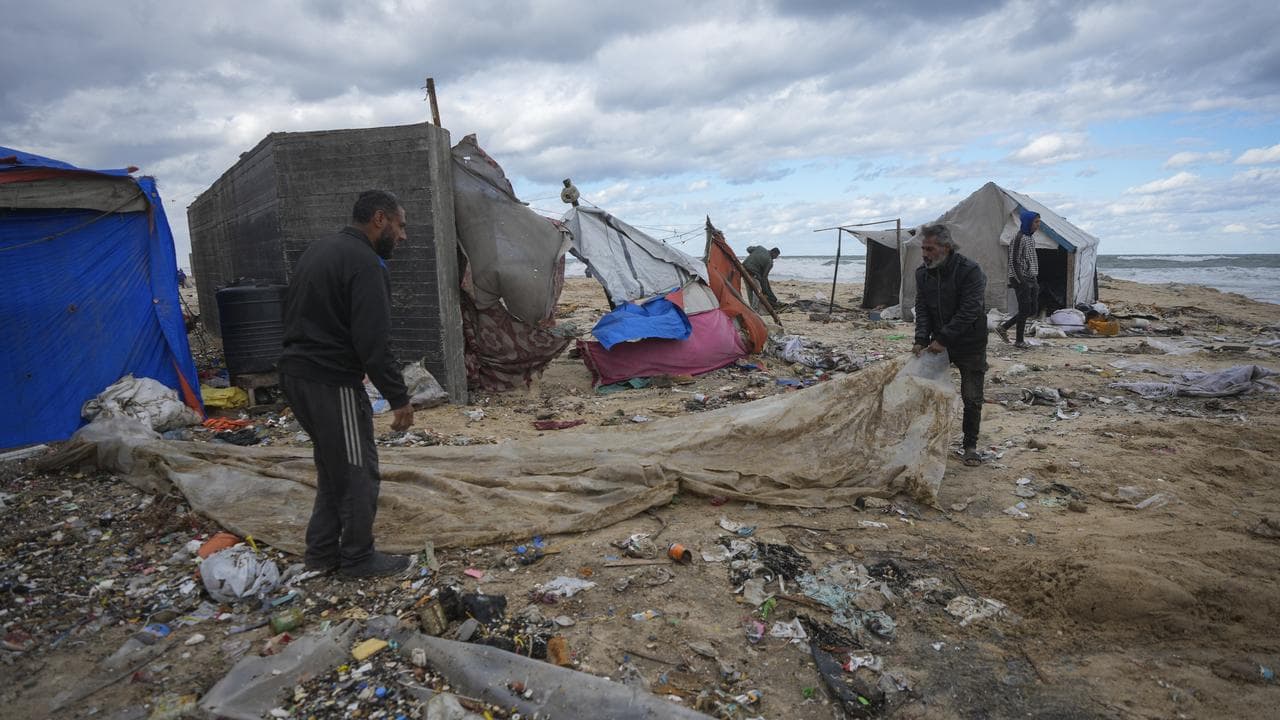 Palestinians fix a tent at a camp for displaced residents