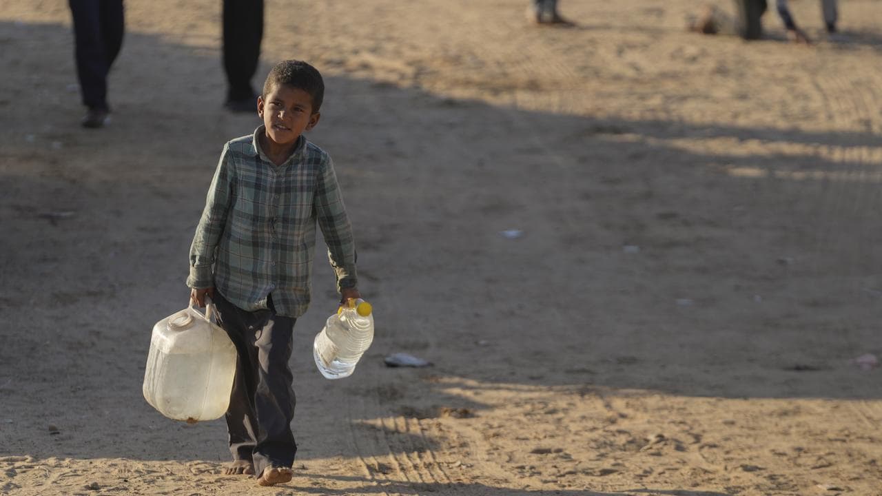 A Palestinian boy carries jerrycans of water