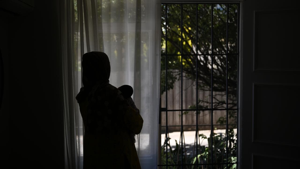 A woman stands holding a child