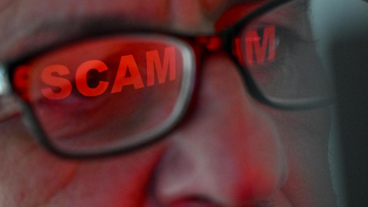 The word ‘scam’ reflected in a person’s glasses 