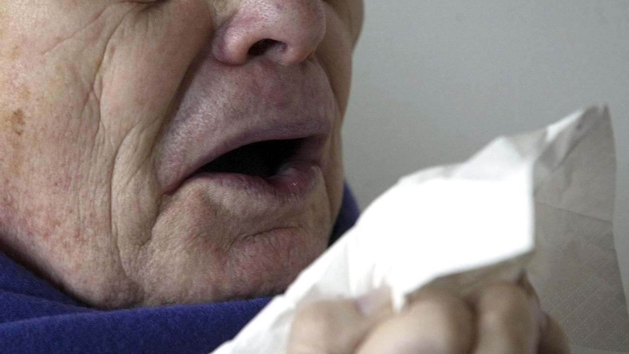 Person sneezing into a tissue.