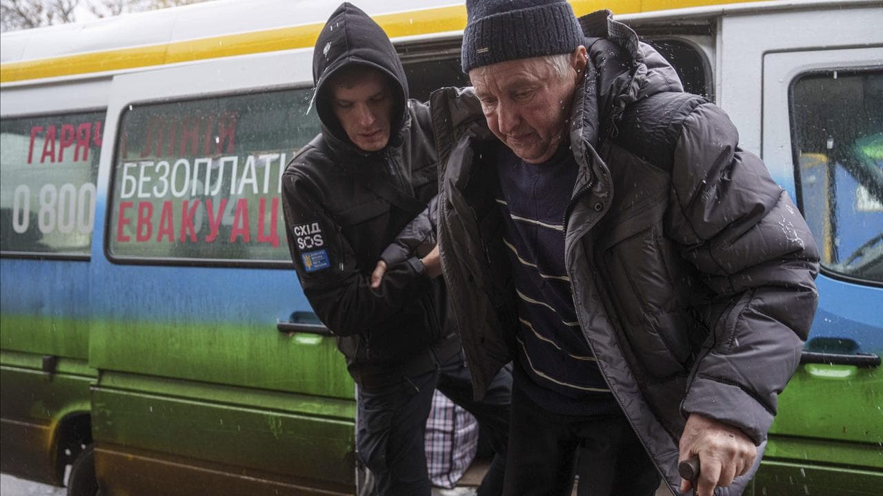 An elderly man to walks from a bus after evacuation from the frontline