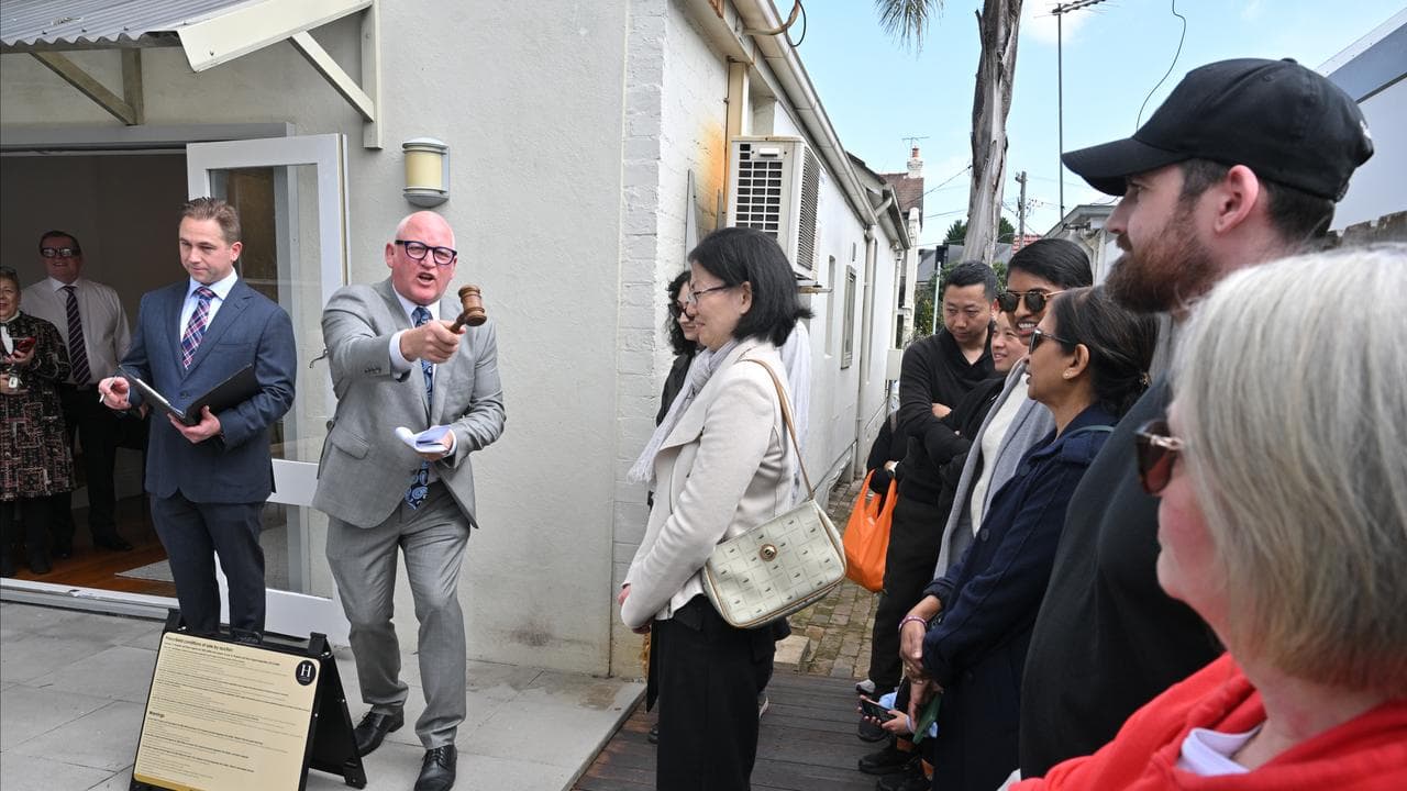 An auctioneer congratulates the winning buyers of a house