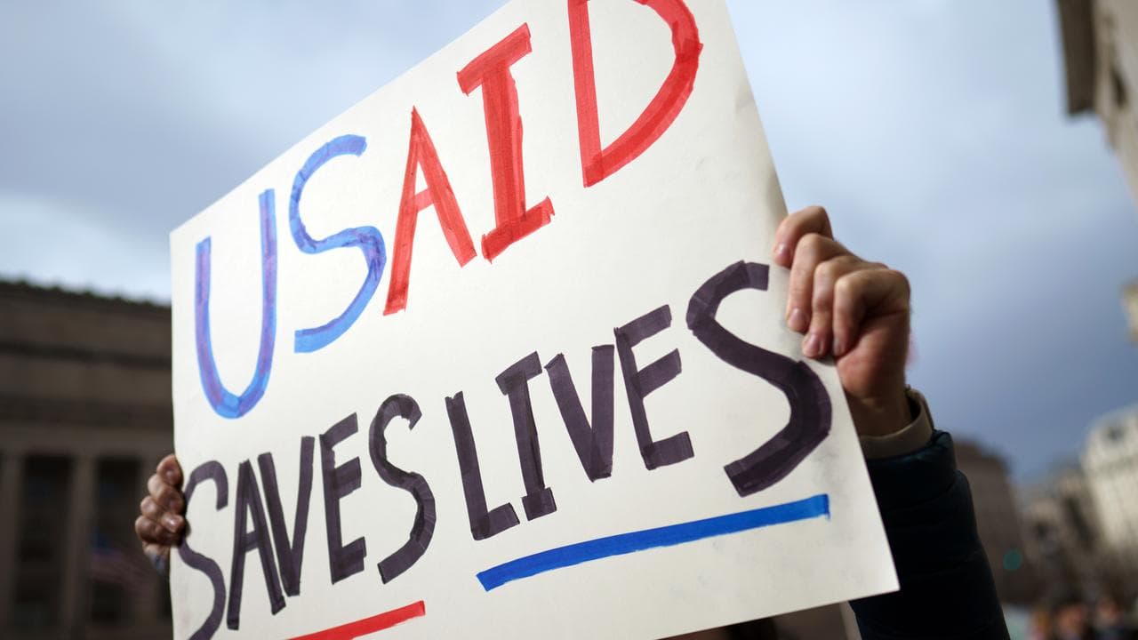 A man holds a sign in protest to the moves to end USAID.