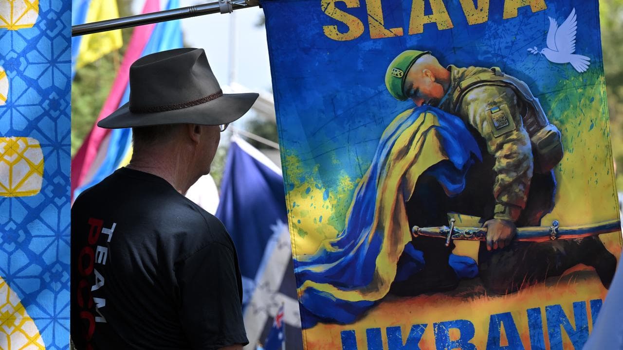 Protesters wave Ukrainian flags and banners at a rally in Canberra