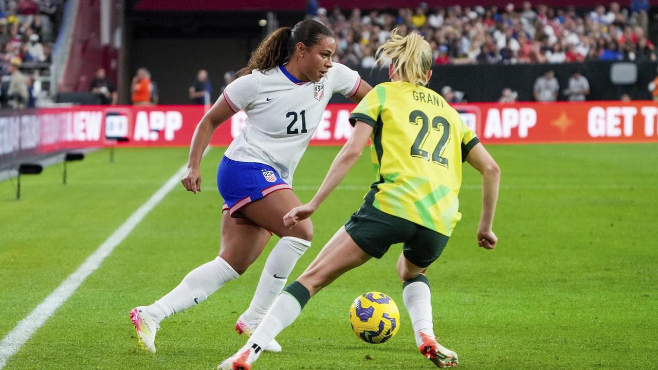 Michelle Cooper (left) dribbles past Australia defender Charli Grant.