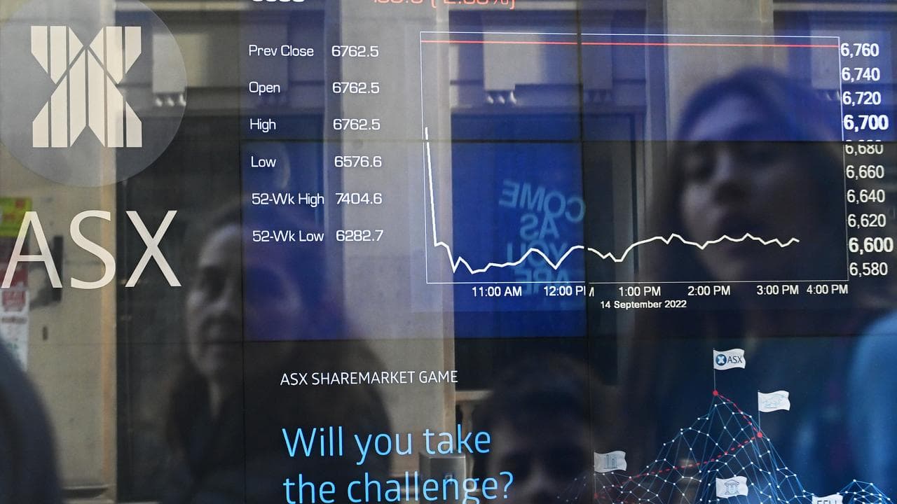 People reflected in the window of an ASX display board