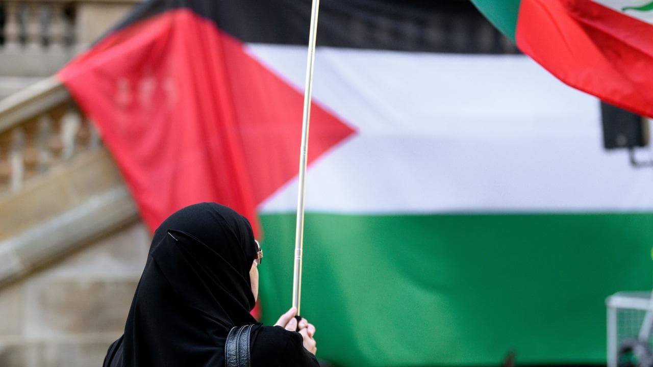 Person in front of Palestinian flag.