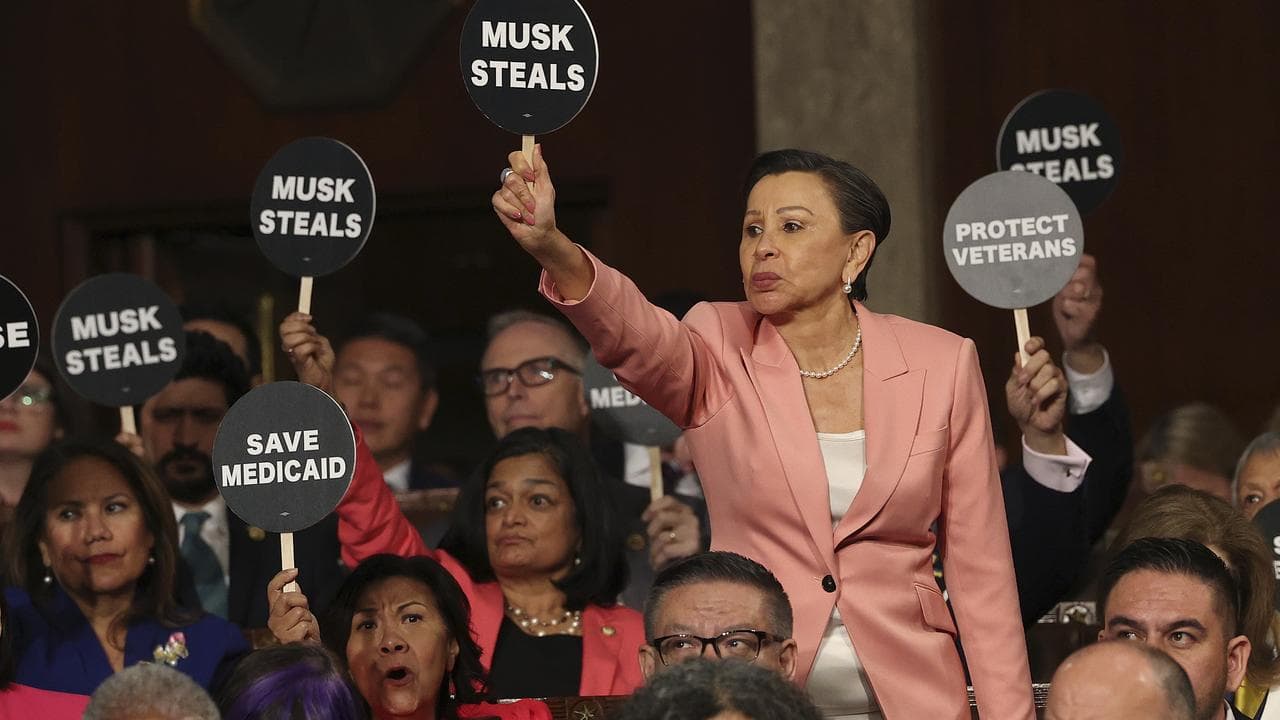 Democrats hold up signs as President Donald Trump addresses Congress