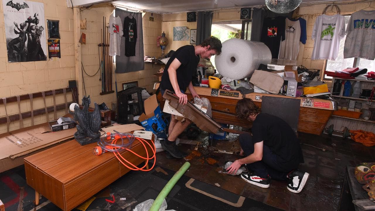 Neighbours clean a house after floodwaters receded in Brisbane.