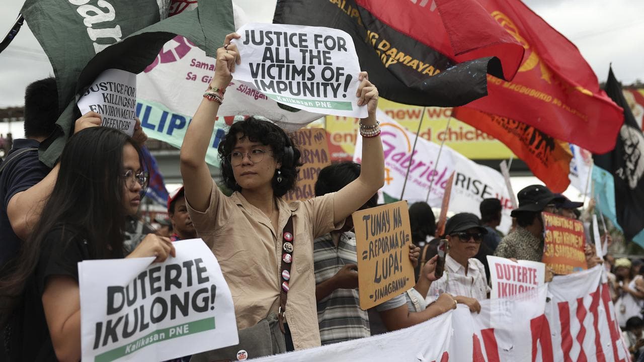 People hold signs against Rodrigo Duterte in Quezon City