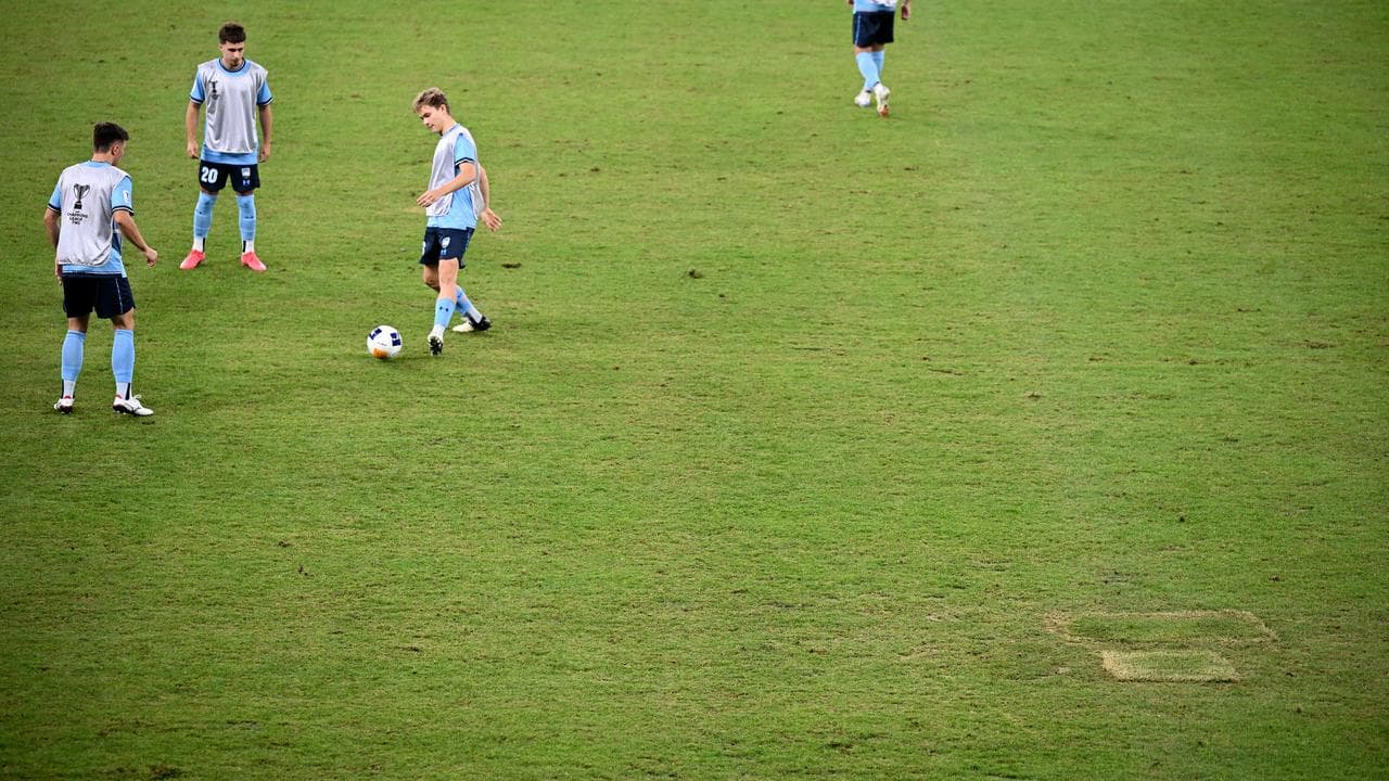 Sydney FC players warming up on poor pitch.