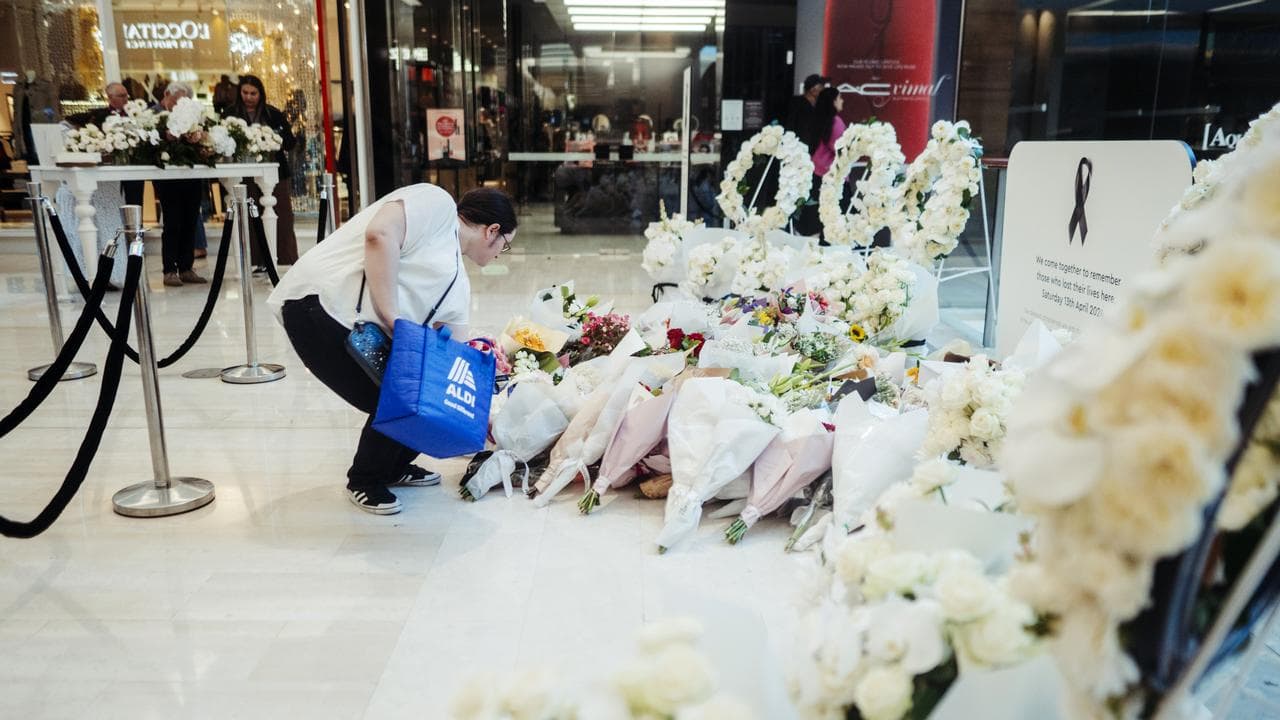Person lays flowers at a memorial at Westfield Bondi Junction