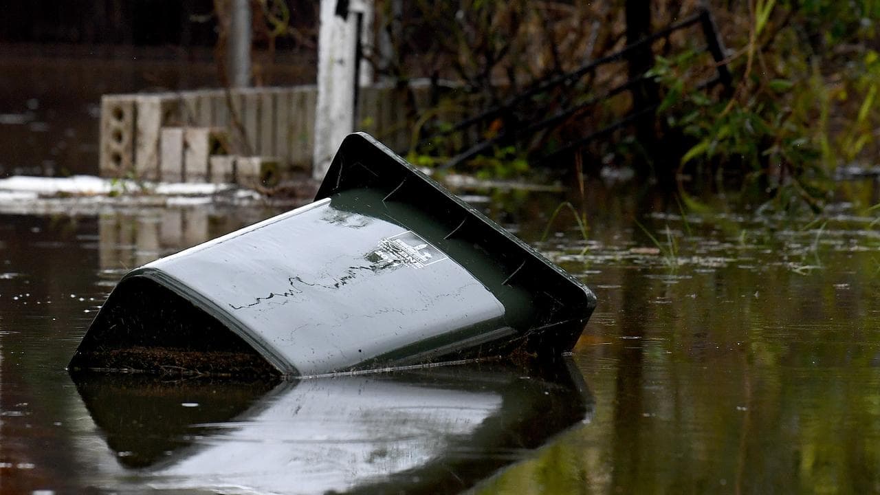 Rubbish bins are seen near flooded houses
