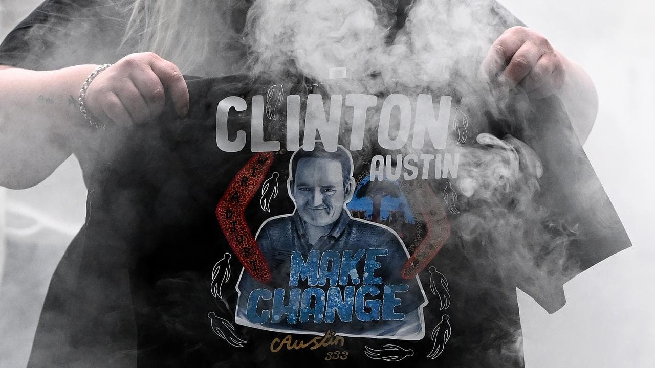 A woman holds a t-shirt showing Clinton Austin