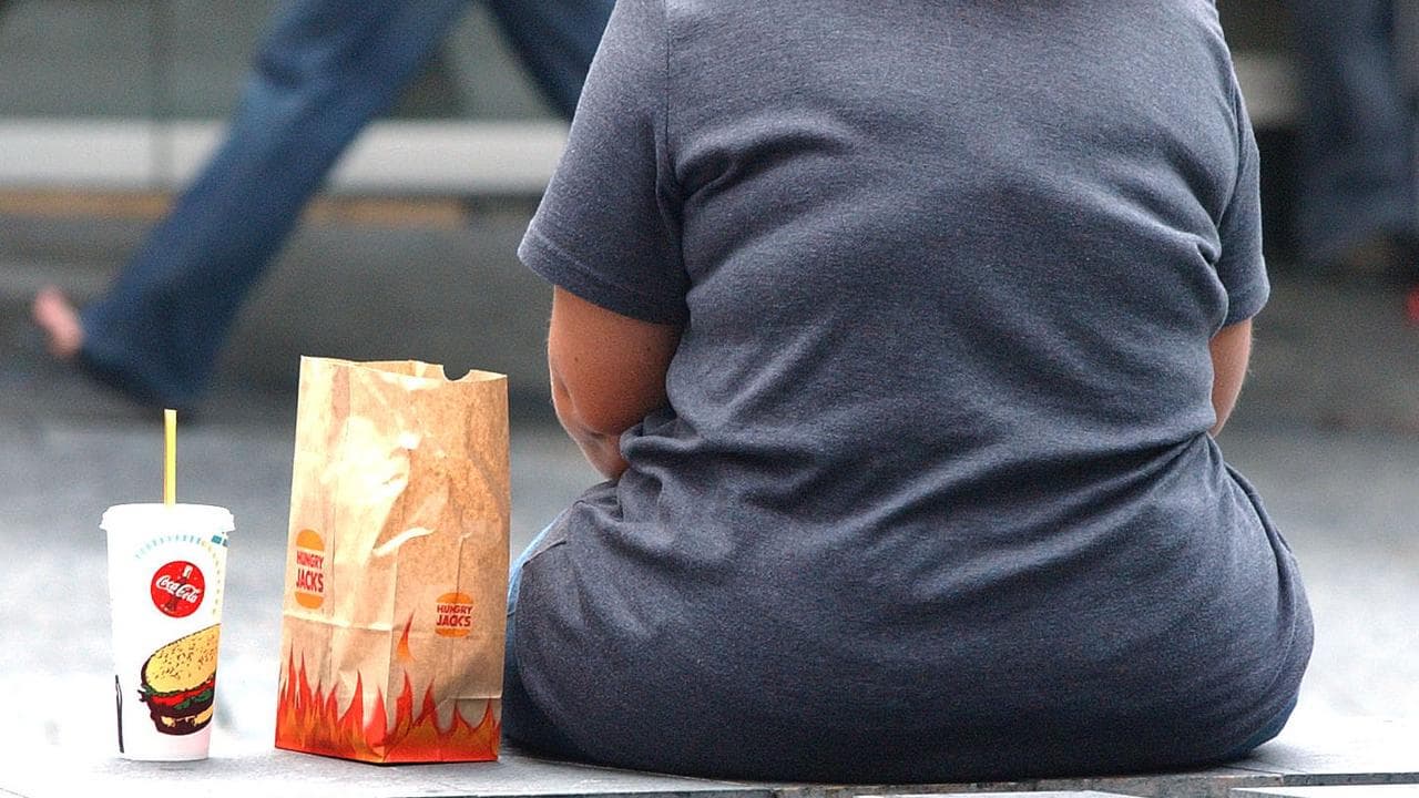 Overweight woman pictured from behind, sat next to Hungry Jacks food.