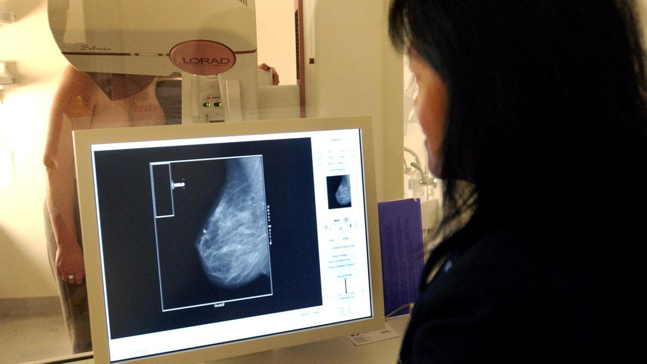 Radiographer performs a mammogram on a patient