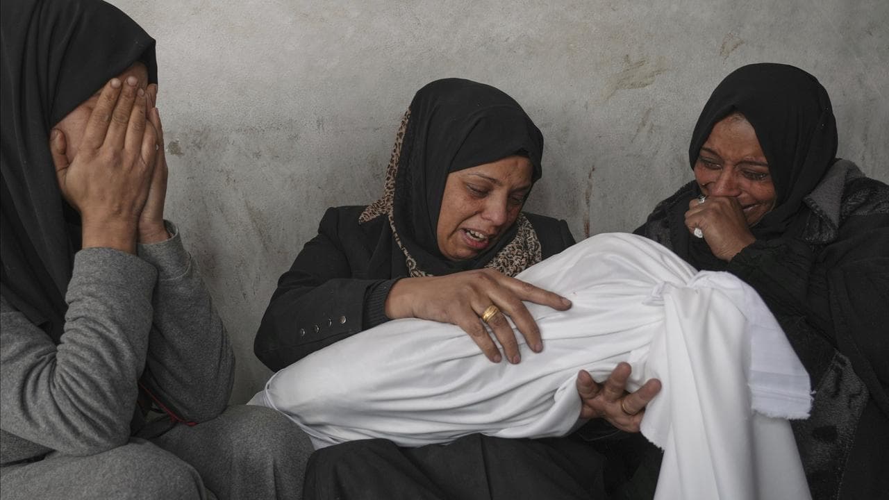 Women hold the body of a 2-year-old child killed by an Israeli strike