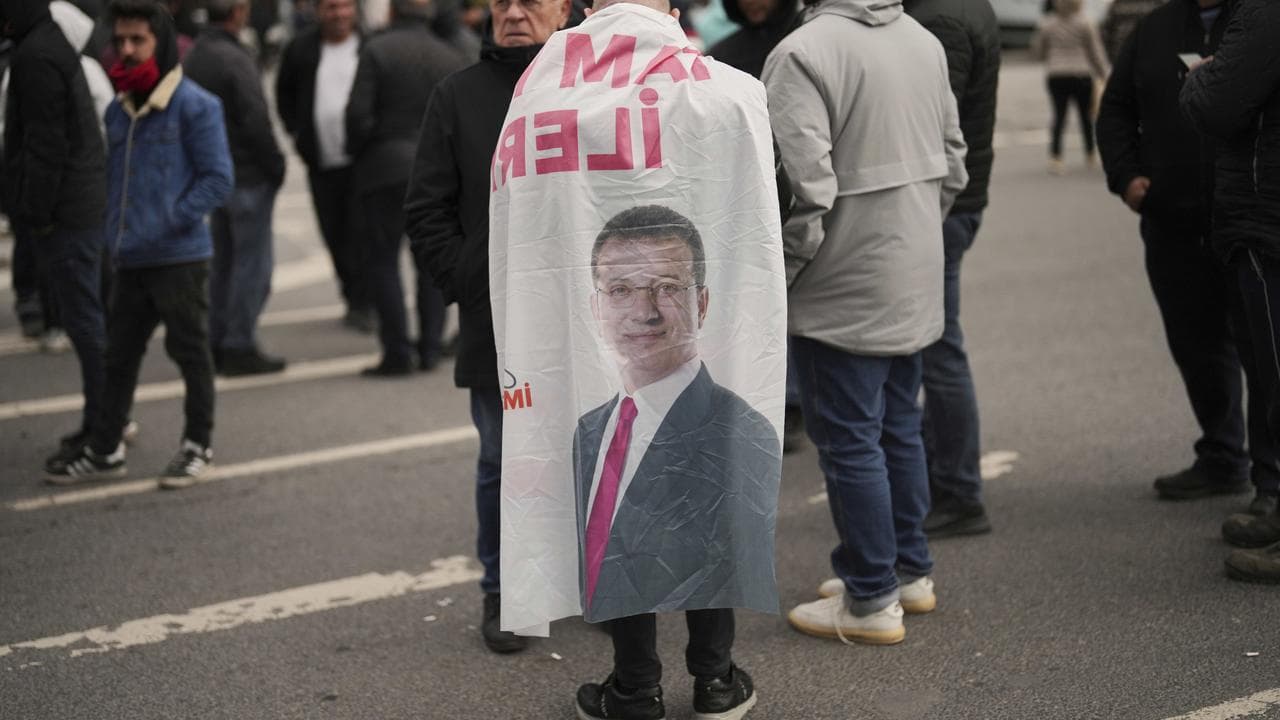 A man wears a banner featuring a photo of Ekrem Imamoglu