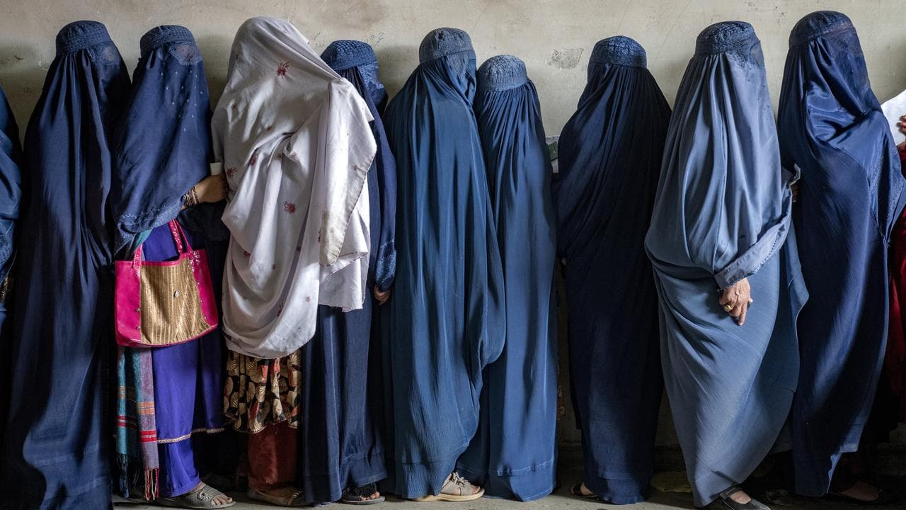 Afghan women wait to receive food rations