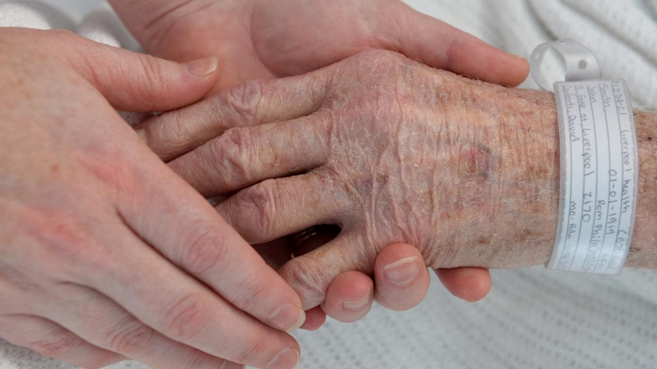 Nurse holds hand of an elderly patient at Liverpool Hospital, Sydney