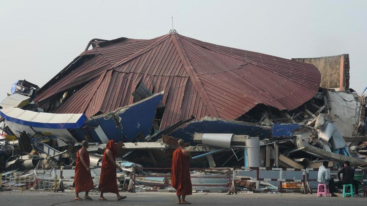 Buddhist monks walk past a collapsed building in Naypyitaw, Myanmar