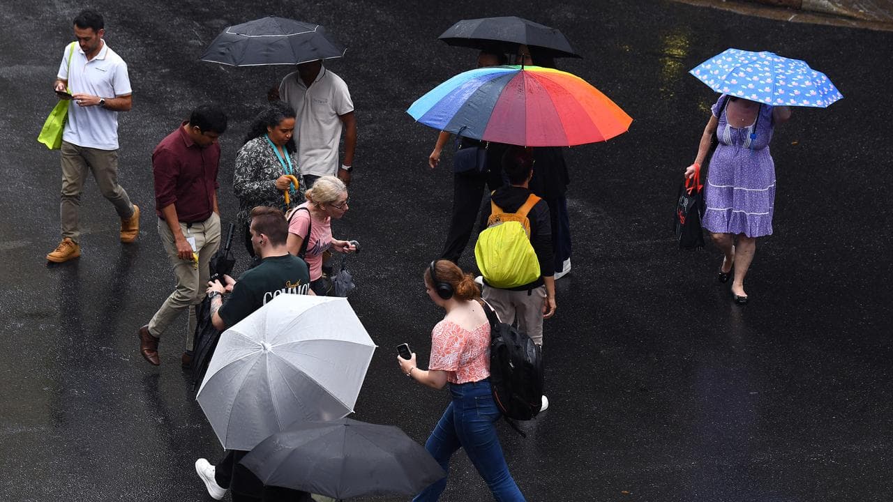 People shelter under umbrellas