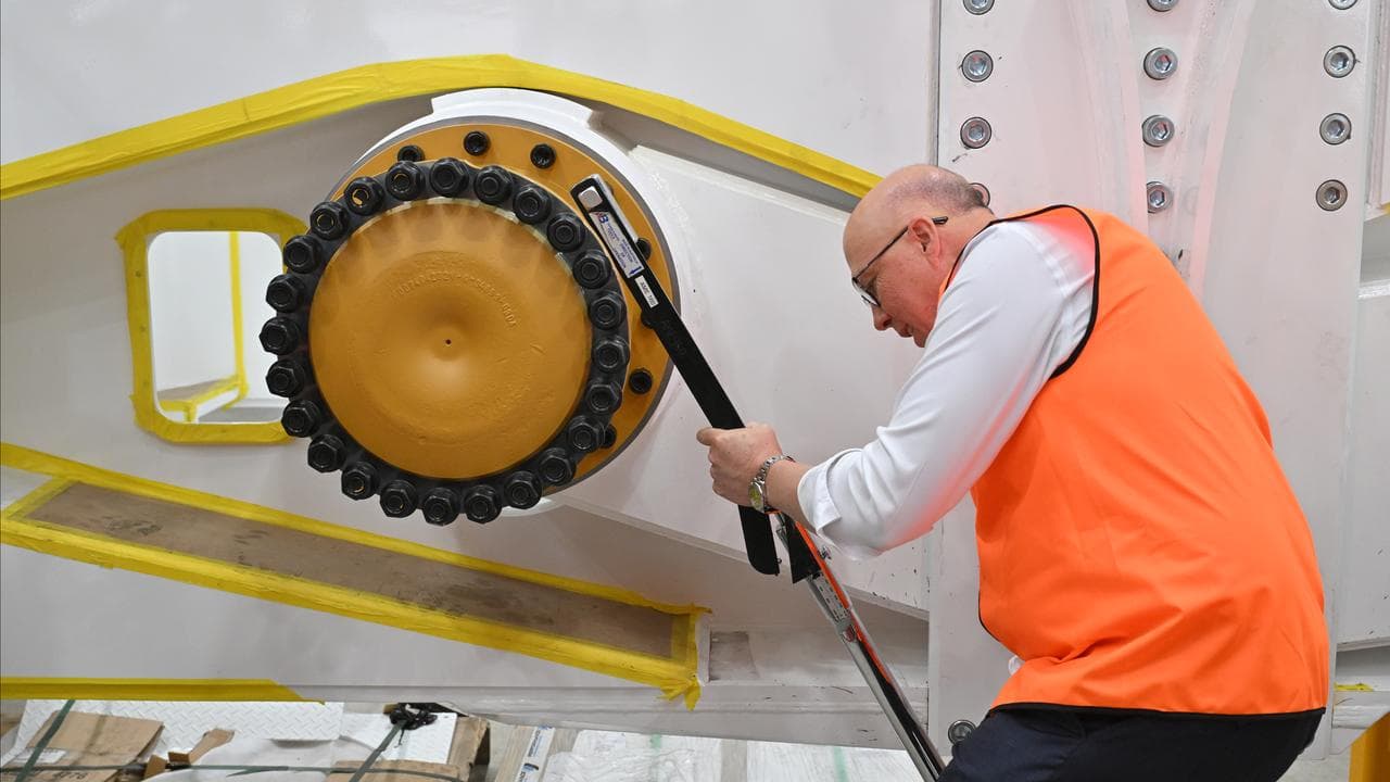 Peter Dutton tightens a wheel nut at Cougar Mining Equipment facility
