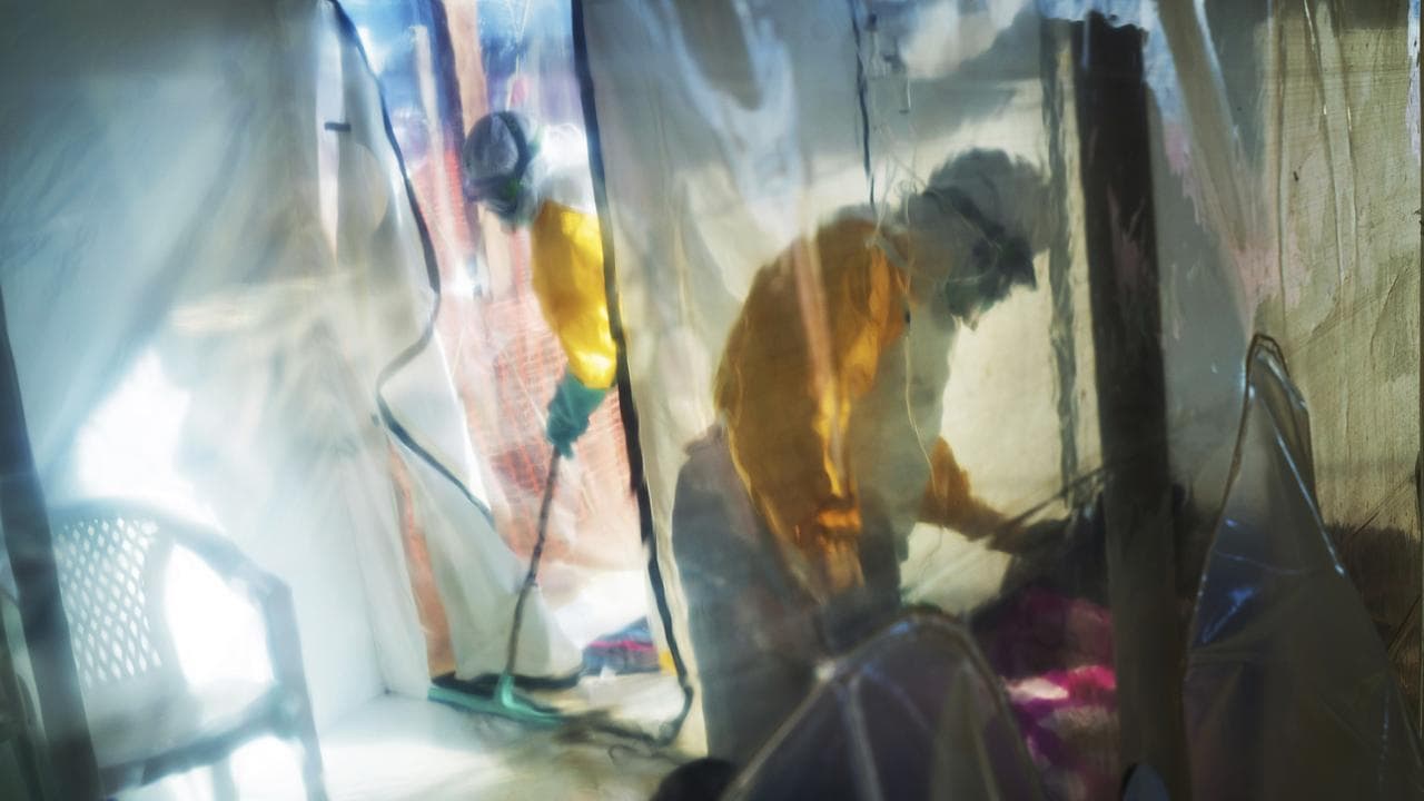 Health workers wearing protective suits tend to an Ebola victim.