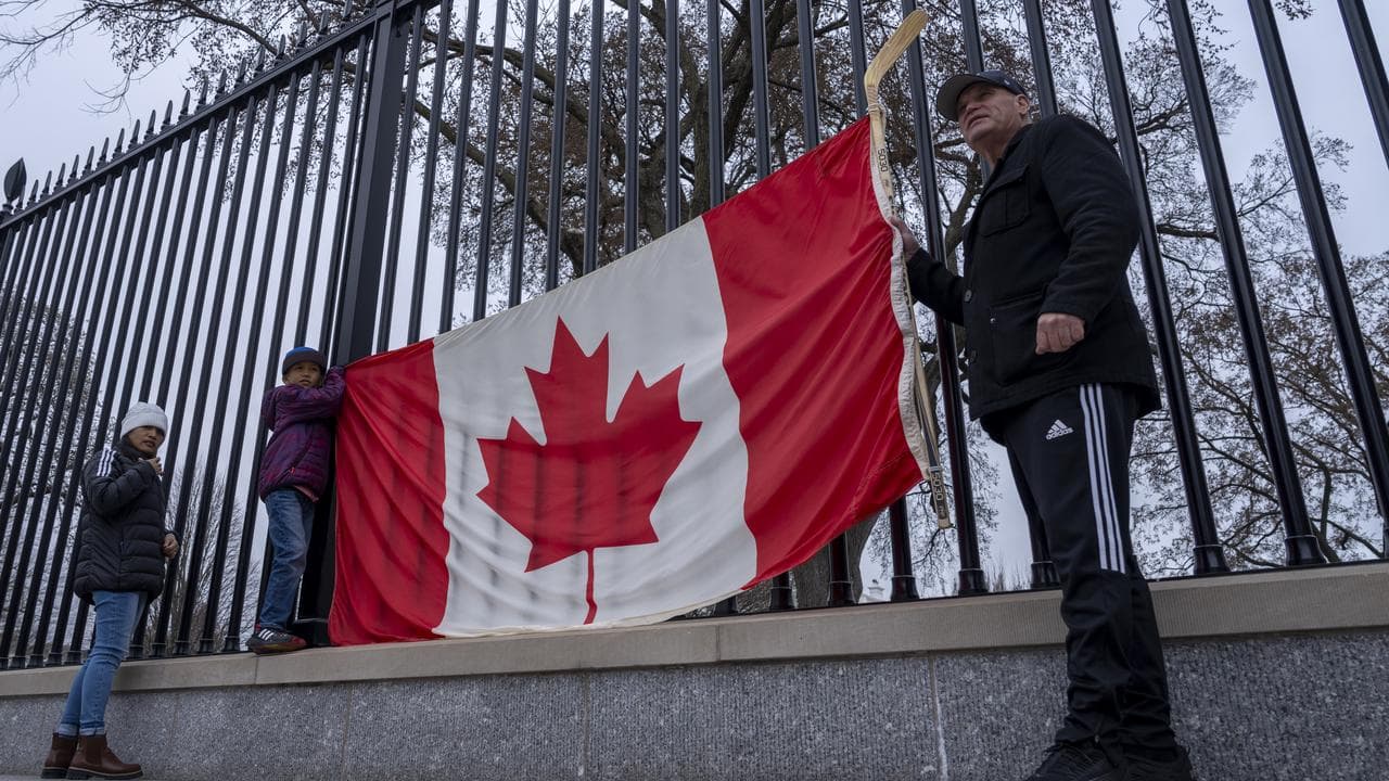 Canadian tourists hold up their country's flag outside the White House
