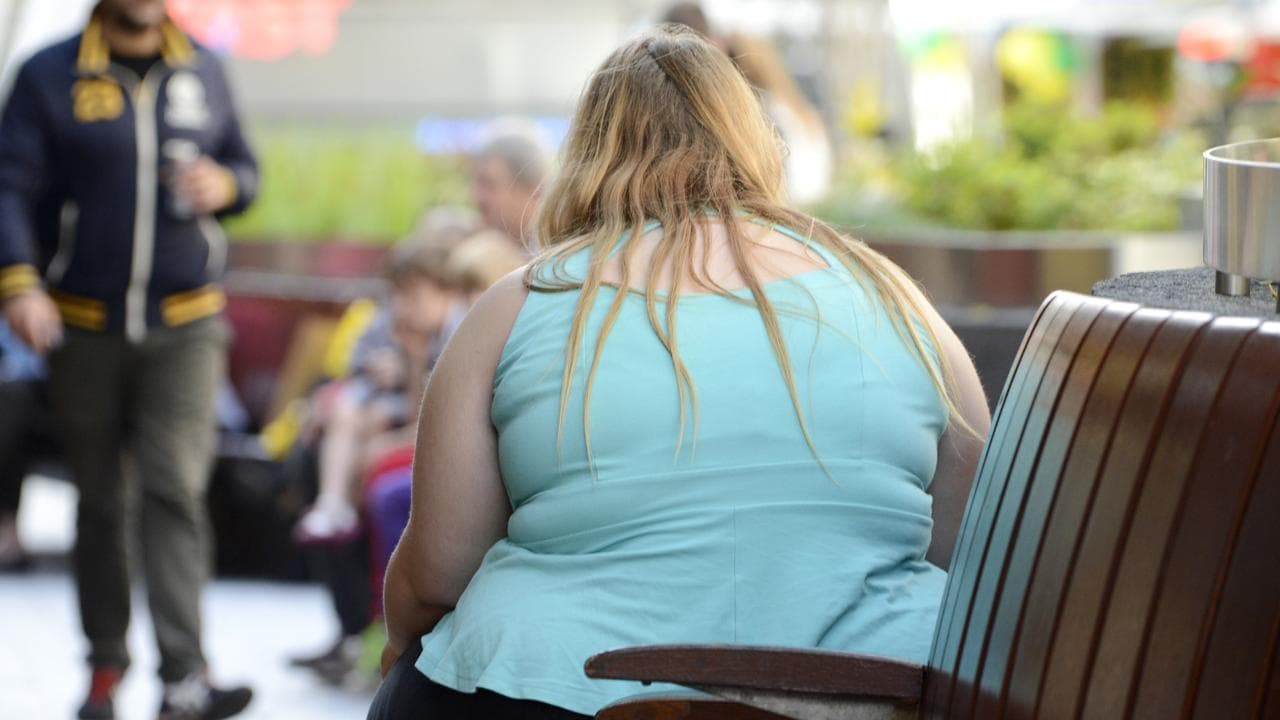 An obese woman on a  street bench.