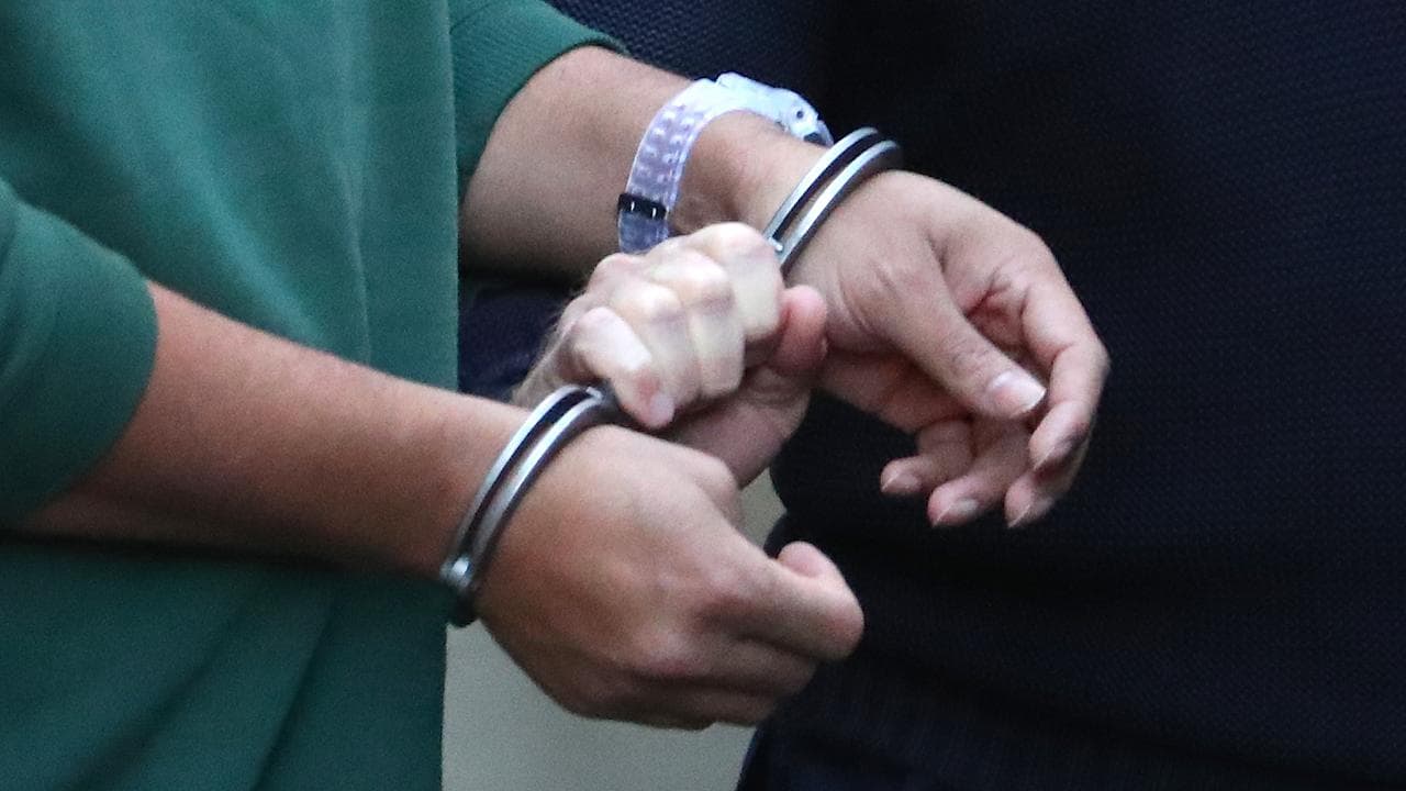 A prisoner is led by handcuffs (file image)
