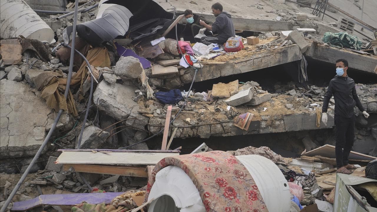 Palestinians sift through the rubble of a building hit by an airstrike