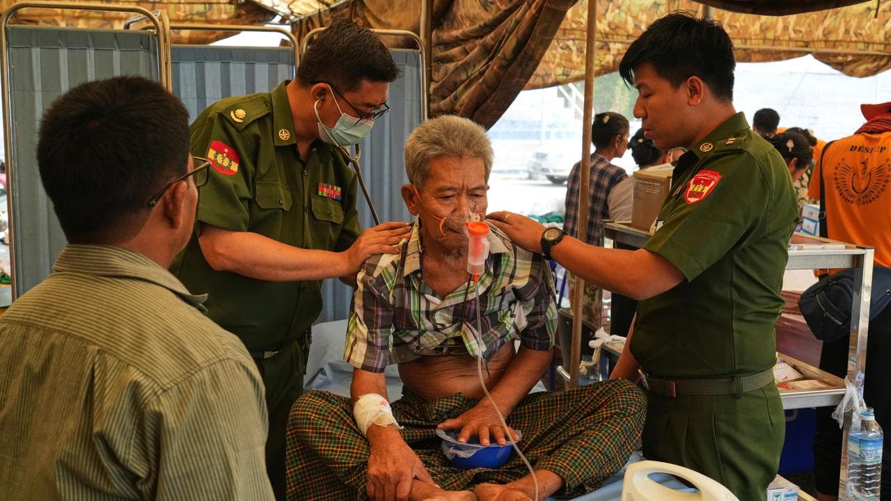 Military medical volunteers give treatments to a patient