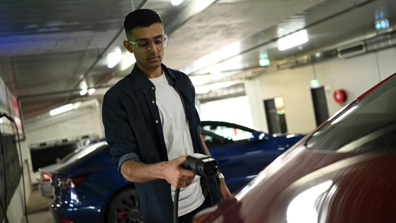 Ridham Chandrani poses for a photo with an electric car in Melbourne