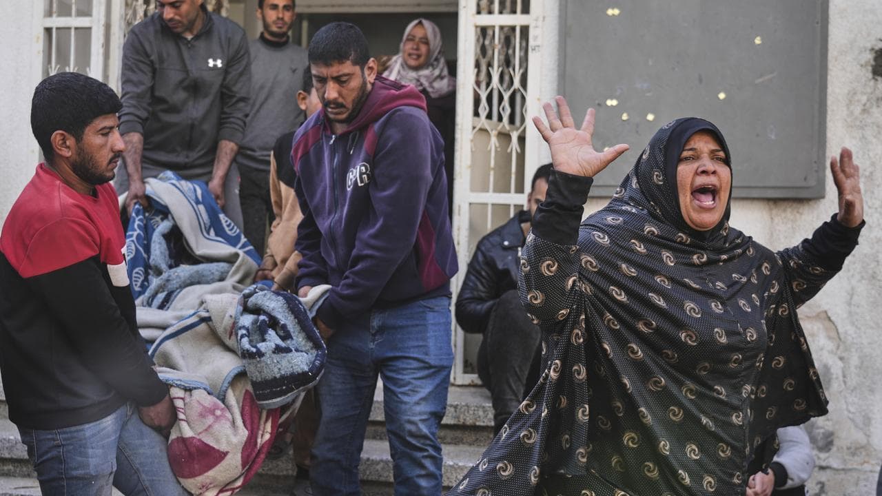 A woman reacts as others carry the body of their relative in Gaza